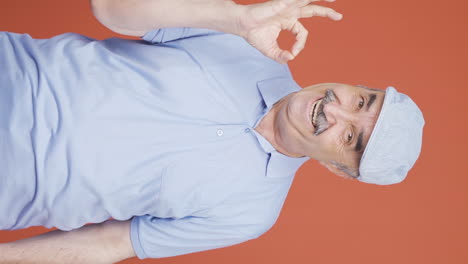 Vertical-video-of-Old-man-making-positive-gesture-at-camera.